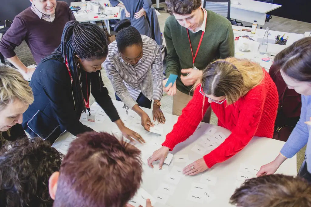 A team leans over a table, sorting cards together during a Talentrade workshop